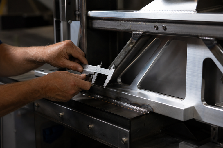 Quality inspection of structural steel and aluminum fabrication with calipers at Curated Fabrication